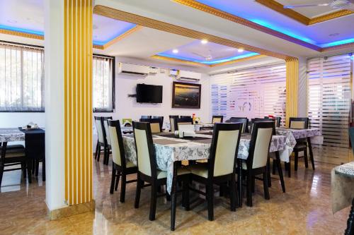 uma sala de jantar com mesas e cadeiras e uma televisão em Athi Resorts em Bogmalo