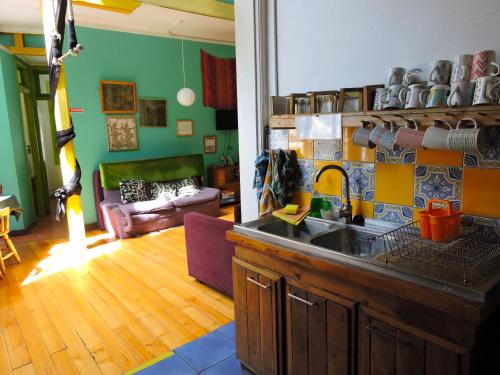 a kitchen with a sink and a living room at Hostal Casa Verde Limón in Valparaíso