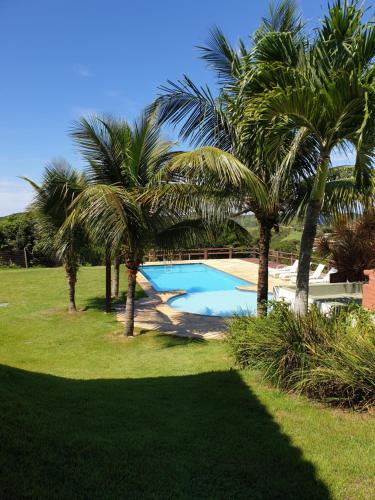 a swimming pool with palm trees in a yard at Lindo Apartamento em Buzios in Búzios