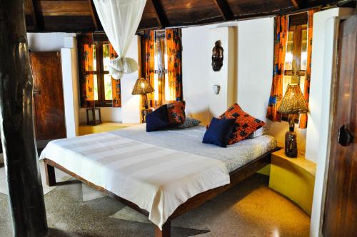 een slaapkamer met een bed met blauwe kussens bij Ankobra Beach Resort in Axim