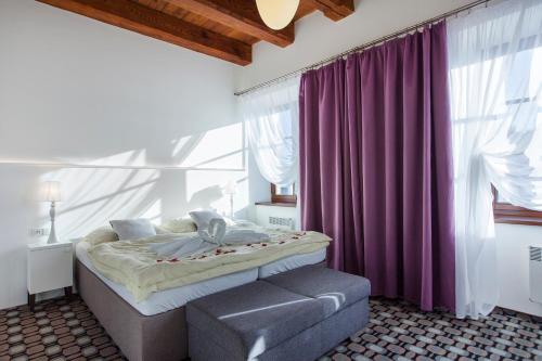 1 dormitorio con cama y cortina púrpura en Hotel Salety, en Valtice