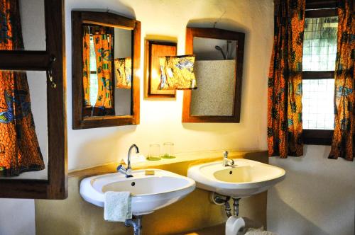 ein Bad mit 2 Waschbecken und Spiegeln an der Wand in der Unterkunft Ankobra Beach Resort in Axim