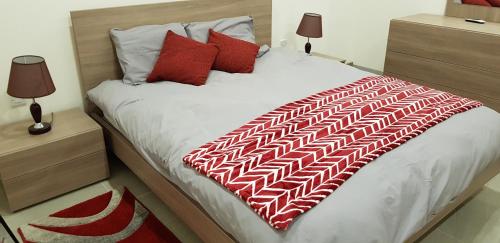 ein großes Bett mit einer roten und weißen Decke drauf in der Unterkunft Fort Cambray Apartment with Spectacular Sea Views in Mġarr