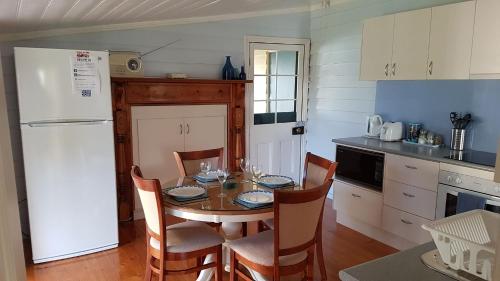 a kitchen with a table with chairs and a white refrigerator at Addies Place Goolwa in Goolwa