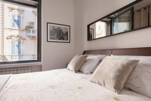 ein Schlafzimmer mit einem Bett mit zwei Kissen und zwei Fenstern in der Unterkunft Via Bozzi Luxury Home in Bari