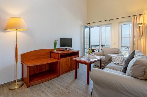 a living room with a couch and a desk with a television at Sur la Mer - Pension Garni in Barth