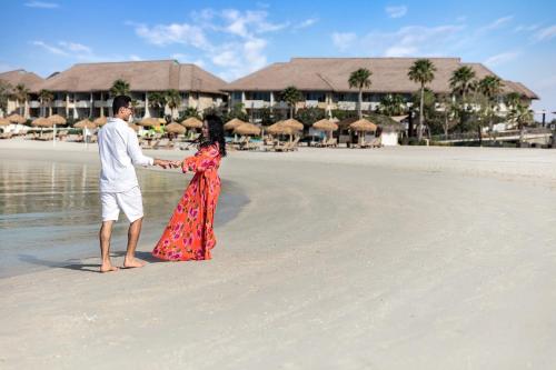 a man and a woman standing on a beach at Banana Island Resort Doha by Anantara in Doha