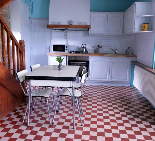 eine Küche mit einem Tisch und Stühlen auf einem karierten Boden in der Unterkunft 31 Chemin de la Croix aux Outils in Paimpol