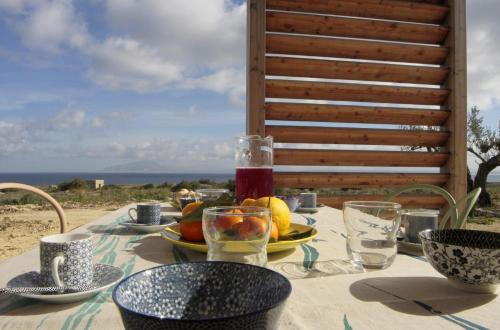 a table with a plate of fruit and glasses at Cala Rossa Lodge in Favignana