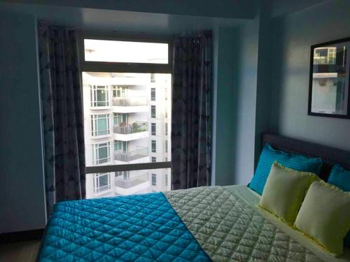 een slaapkamer met een bed en een groot raam bij Ameer Condotel @ Parkside Villa in Manilla