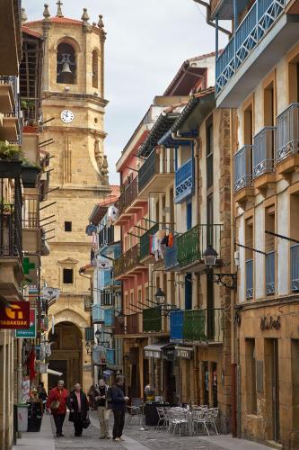a group of people walking down a street with a clock tower at BALENTZIAGA Getaria in Getaria