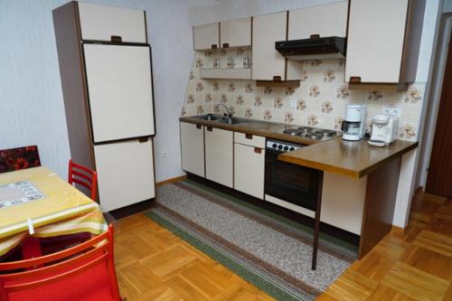 eine Küche mit weißen Schränken, einem Tisch und einer Theke in der Unterkunft Pension Sonnenblume in Donnerskirchen