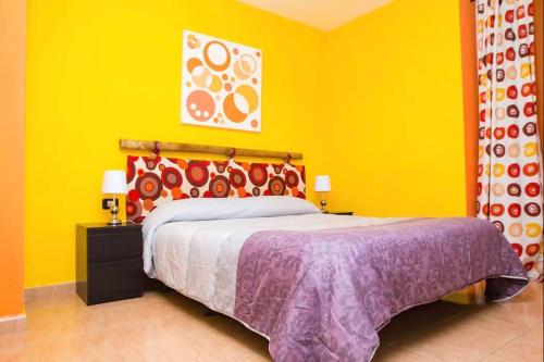 ein Schlafzimmer mit einem Bett mit gelber Wand in der Unterkunft Los Cristianos Tenerife in Los Cristianos