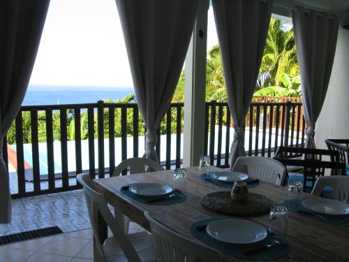 a wooden table with chairs and a view of the ocean at GÏTE REVE CARAIBES " LA PERLE " in Bouillante