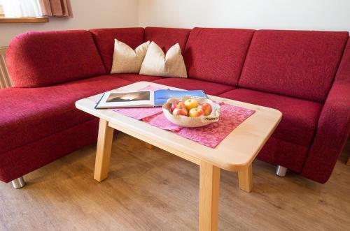 a red couch with a table with a bowl of fruit on it at Ferienhaus Aurora in Kals am Großglockner