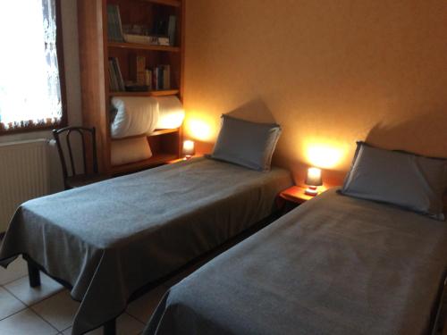 two beds in a small room with two lamps at vue sur les montagnes dans maison au calme in Saint-Joseph-de-Rivière
