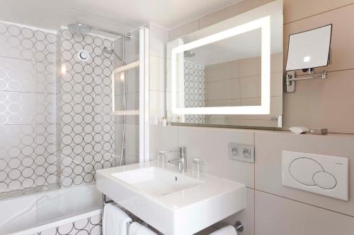 La salle de bains blanche est pourvue d'un lavabo et d'un miroir. dans l'établissement Hotel Massena, à Paris