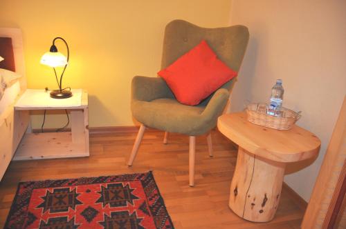 a living room with a chair with a red pillow at Gästehaus Alpenblick in Mutters