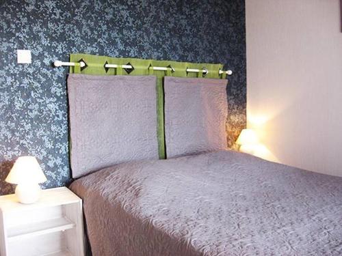 sypialnia z łóżkiem z fioletową pościelą i niebieską tapetą w obiekcie Les Frênes w mieście Retournac