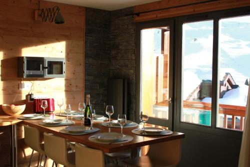 - une table en bois avec des chaises et des verres à vin dans l'établissement Carene - Belle plagne - 8 personnes, à Belle Plagne