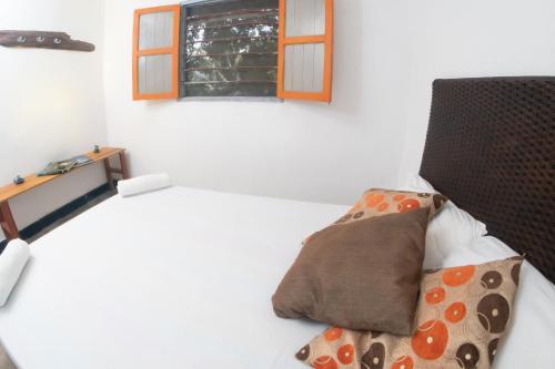 a bedroom with a bed with a window and a pillow at Entre Bosques Tayrona in Los Naranjos