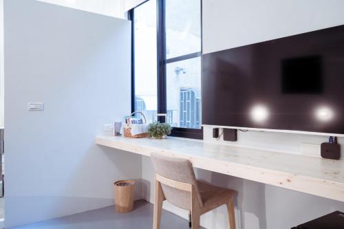 a desk with a television and a chair in a room at UNS B&B in Kaohsiung