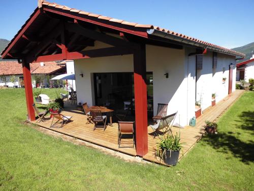 a wooden deck with chairs and a table in a yard at Maison Fleurie in Uhart-Cize