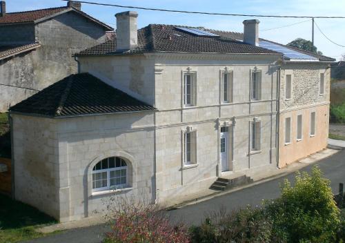 an old stone building with a chimney on a street at Chambres d'Hôtes Le Bourdieu in Soulignac