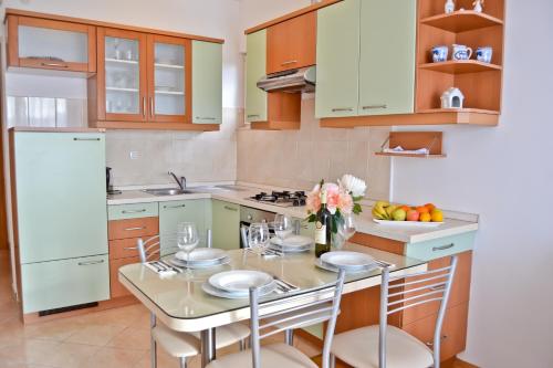 eine Küche mit einem Tisch mit Stühlen und einem Kühlschrank in der Unterkunft Apartman MiMe in Stanići