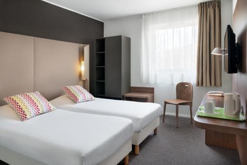 カトヴィツェにあるカンパニール カトワイスのベッド2台と窓が備わるホテルルームです。