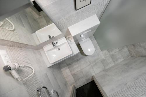 a bathroom with a white sink and a shower at Senamiesčio apartamentai in Tauragė