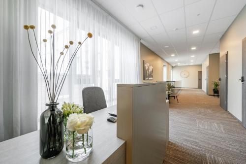 an office with a table with flowers in a vase at Senamiesčio apartamentai in Tauragė