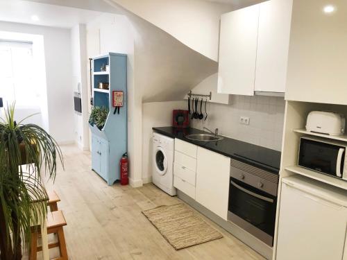 a kitchen with white cabinets and a sink and a dishwasher at Lisbon City Studio Apartment in Lisbon