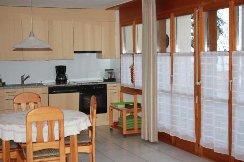 una cocina con mesa y algunas sillas y una mesa y una cocina con en Sut baselgia, en Andeer