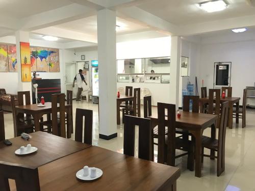 un ristorante con tavoli e sedie in legno e una persona sullo sfondo di Alina Budget Hotel a Kaduwela