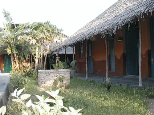 ein Haus mit einem Grasdach und einem Hof in der Unterkunft Patio dos quintalinhos - Casa di Gabriele in Ilha de Moçambique