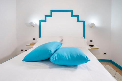 a bed with two blue pillows on it at Maison M. - Luxury Apartment in Piazza Tasso in Sorrento