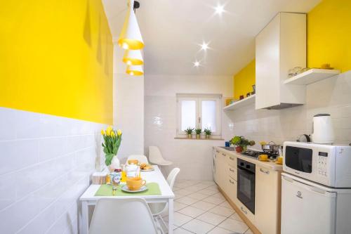 a kitchen with a small table and a yellow wall at Maison M. - Luxury Apartment in Piazza Tasso in Sorrento