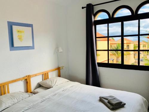 1 dormitorio con cama blanca y ventana en Vacation House La Cebada, en Costa Calma