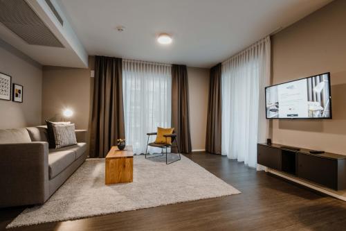 a living room with a couch and a flat screen tv at Timehouse Serviced Apartments in Munich