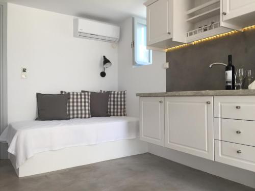 a white kitchen with a bed and a sink at L’arco Milos Suite in Adamas
