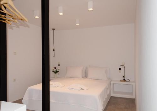 a bedroom with a white bed and a mirror at L’arco Milos Suite in Adamas