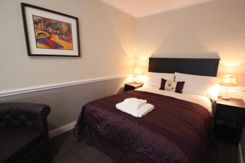 a hotel room with a bed with two towels on it at The Dibbinsdale Inn in Bromborough