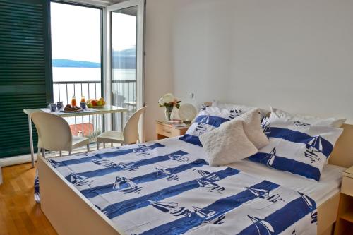 een bed met een blauw en wit dekbed en een tafel bij Studio Berni in Stanići