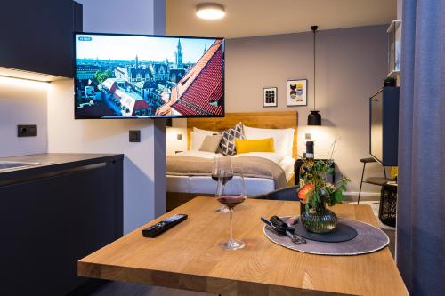 a room with a table with a wine glass and a tv at Timehouse Serviced Apartments in Munich
