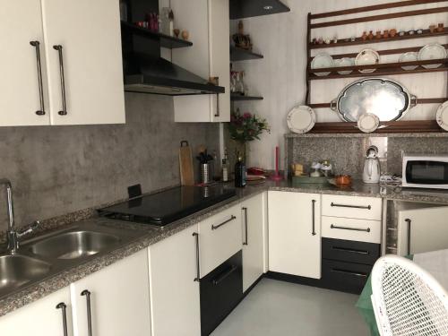 a kitchen with white cabinets and a sink at Appartamento Country House Menaggio in Menaggio