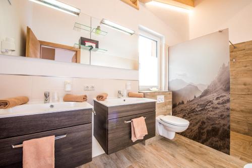 a bathroom with a sink and a toilet and a window at Stockis Mountaindestillerie - Appartements in Leogang