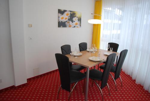 a dining room with a table and black chairs at Apart Holidays in Morschach