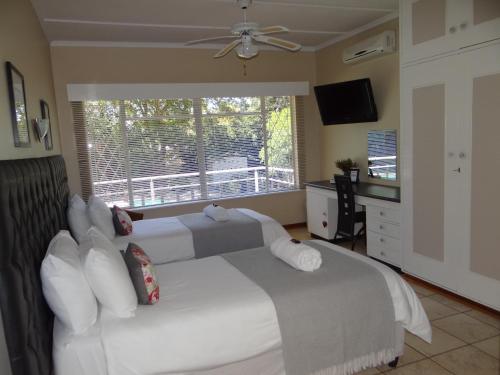a bedroom with two white beds and a window at CREDO Guest House in Bloemfontein
