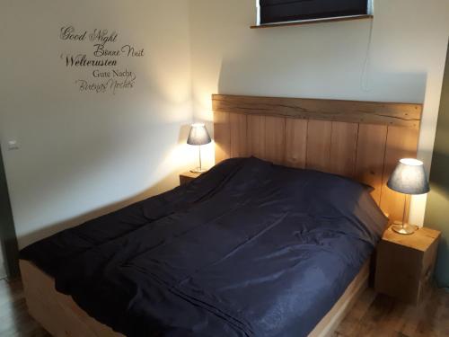 a bedroom with a bed with a blue comforter and two lamps at Aan de Kwakel in Maasland